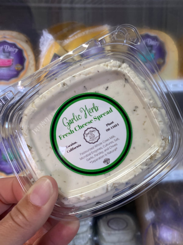 Image contains a tub of Garlic Herb fresh cheese spread in a tamper proof container. 