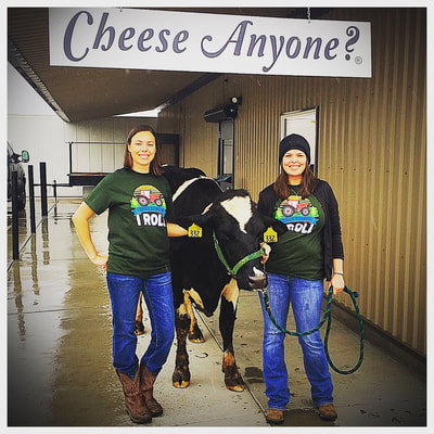 Cheese Anyone? Image includes the Stuyt Sisters with a Holstein cow under their Cheese Anyone welcome sign. 