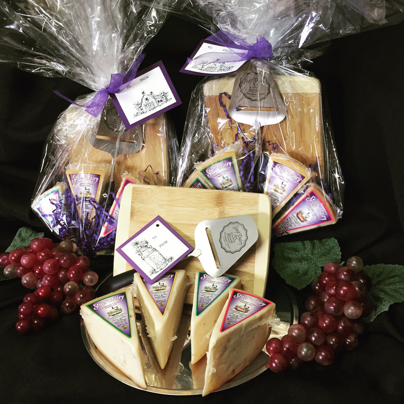 Image contains a gift set including four pieces of cheese in a cellophane bag with a cheese slicer. 
